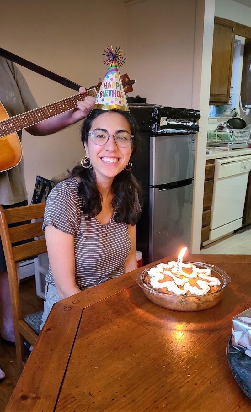 Sunhwa in a Happy Birthday party hat with a lit candle